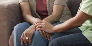 Mother and daughter holding hands on sofa